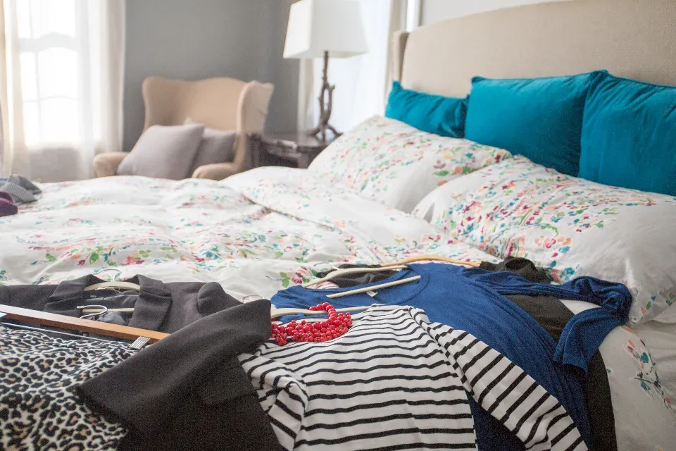 Vêtements empilés sur un lit défait, faute de rangement attribué