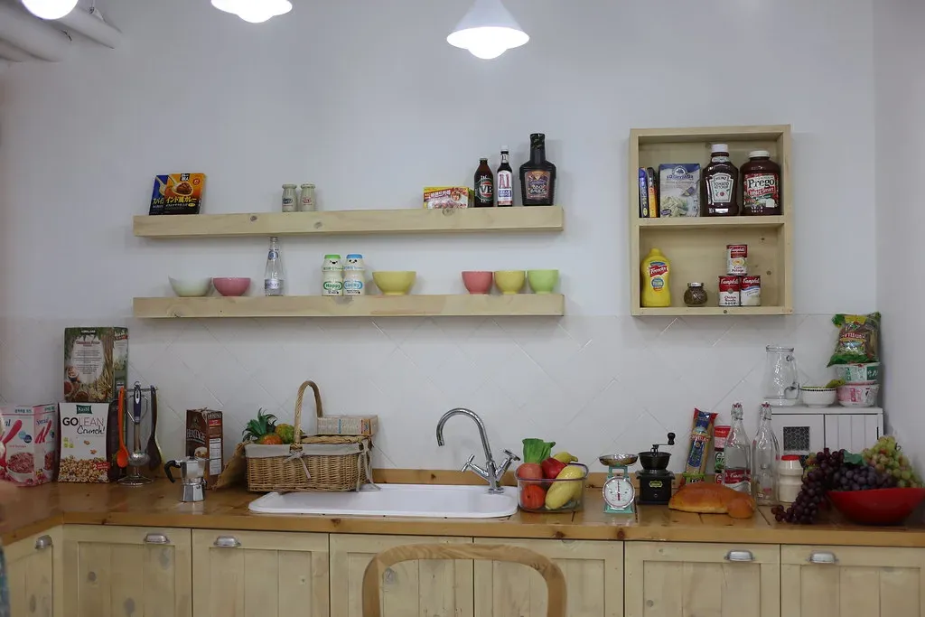 Petite cuisine avec étagères murales ouvertes, bocaux et vaisselle courante à portée de main