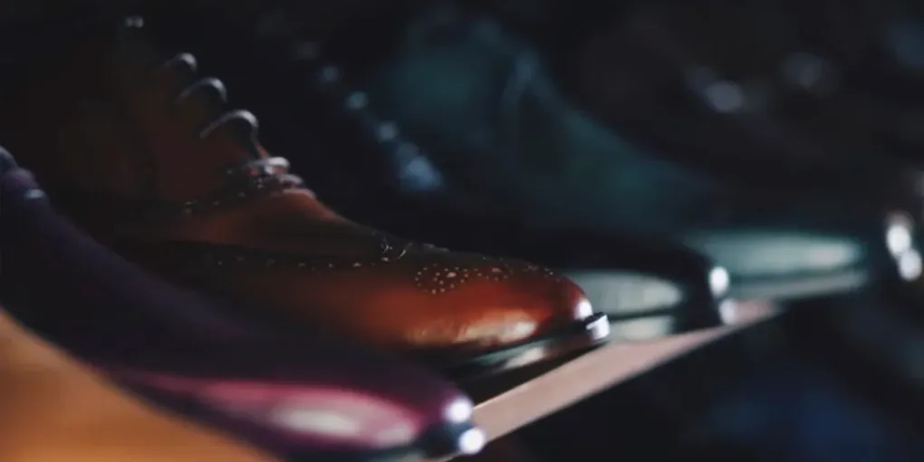 Paires de chaussures en cuir alignées sur une étagère basse près de la porte