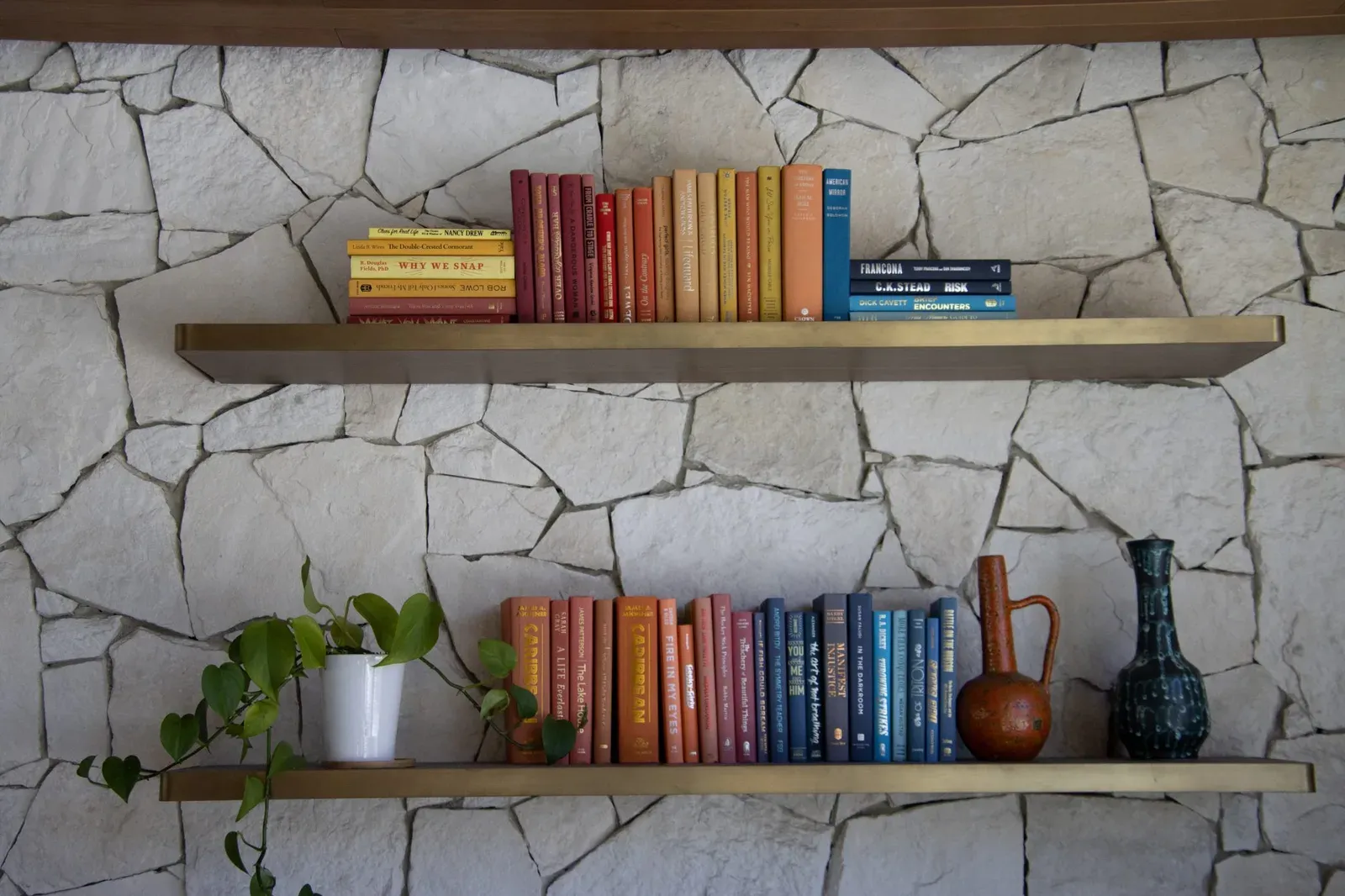 Étagères murales garnies de livres et de plantes, fixées au-dessus d’un canapé